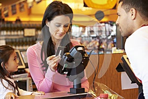 Mother Paying For Family Shopping At Checkout With Card