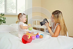 Mother photographer photographing of her baby on camera.