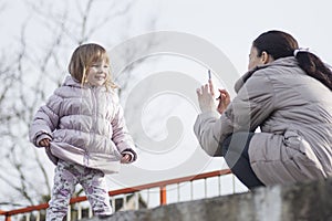 Mother photographing her posing daughter