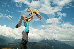 Mother picks up daughter in her arms. concept of a happy family. hot summer day. horizontal picture