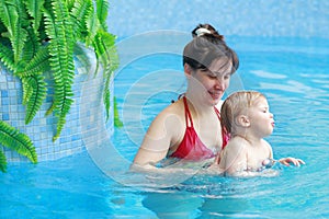 Mother play with her child in swimming-pool