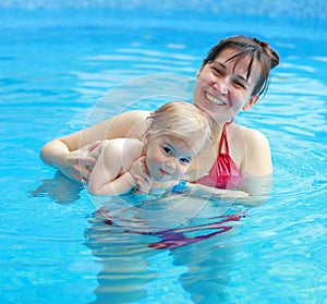 Mother play with her child in swimming-pool