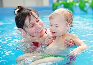 Mother play with her child in swimming-pool