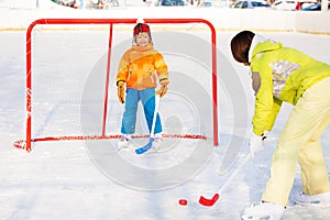 Mother play ice hockey with son outside