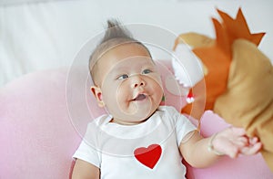 Mother playing animal puppet with her infant baby boy on the bed room at home