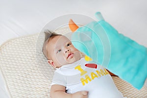 Mother playing animal puppet with her infant baby boy on the bed room at home