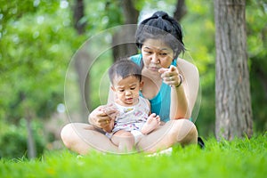 Mother playing with baby boy on green grass