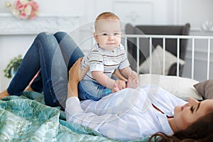 Mother playing with baby lying on bed