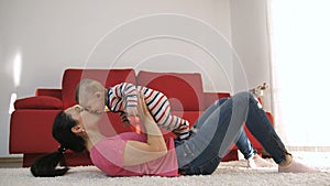 Mother playing with baby son at home lifting him