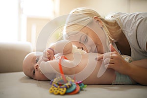 Mother playing on bed with her baby boy at home. Close