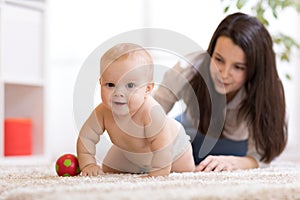 Mother playing with creeping on floor baby