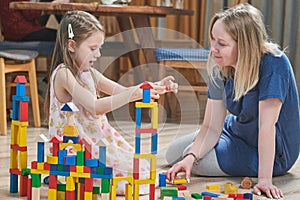 Mother playing with girl with blocks indoors