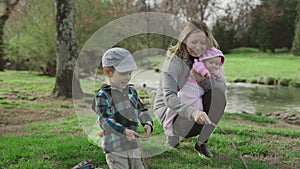 Mother playing and having fun with her little baby girl and little son, spring park. Happy mom and children in the park