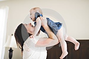 Mother playing with her baby in the bedroom