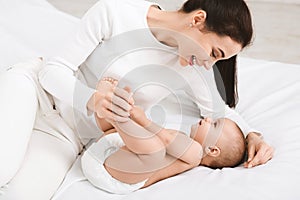 Mother playing with her baby in bedroom.