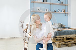 Mother playing with her baby in the bedroom. Happy loving family.