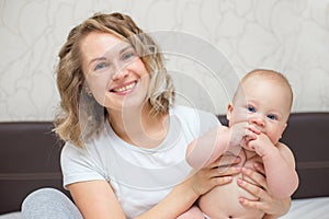 Mother is playing with her baby son in the bedroom