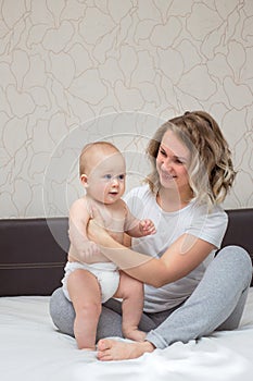 Mother is playing with her baby son in the bedroom
