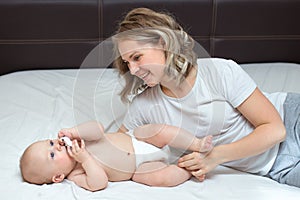 Mother is playing with her baby son in the bedroom