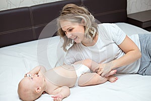 Mother is playing with her baby son in the bedroom
