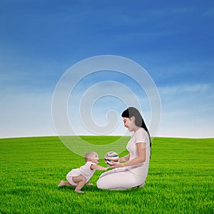 Mother playing with her baby in spring green field