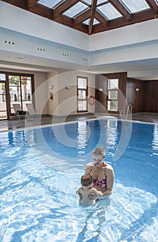 Mother playing with her baby at swimming pool indoor