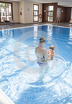 Mother playing with her baby at swimming pool indoor