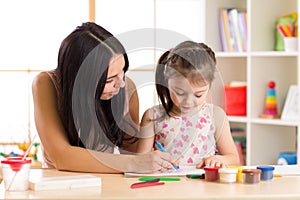 Mother playing with her child daughter, drawing together