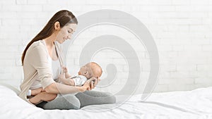 Mother playing with her little baby in bedroom