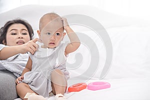 Mother playing with her little infant girl in bedroom. Parent having a happy time together