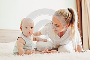 Mother playing with her newborn baby son at home. Family having fun sitting on bed in bedroom. Mother`s day