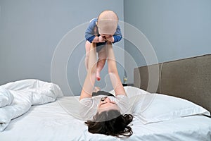 Mother playing with son, smiling woman holding baby in arms