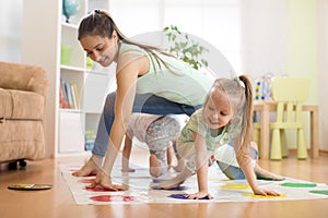 Mother playing twister with her children daughters. Happy family have a fun time in holiday
