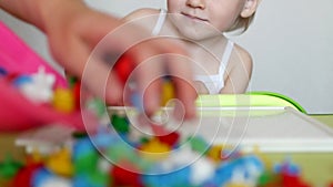 Mother plays with the child in the game developing motor skills, collect a children`s multi-colored mozayku the designer