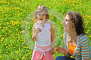 Mother plays with girl which breath on dandelion photo