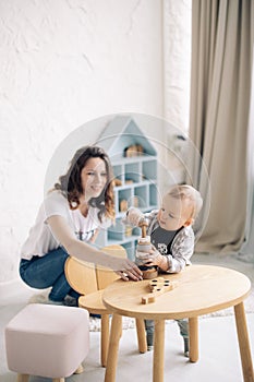 Mother plays together with her toddler boy and builds pyramid tower