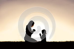 Mother Praying with her Young Child Outside at Sunset