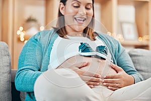 Mother, pregnancy and pregnant stomach in hands, woman with shoes for baby, excited about childbirth and happy at family