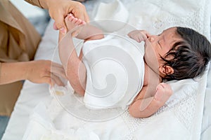 Mother prepare tto change diaper or napkin for newborn baby lie on white bed after she excrete pee or stool photo