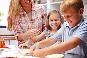 Mother preparing pizza with kids