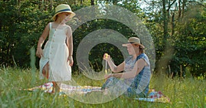 Mother and preschool daughter blow bubbles in the park.