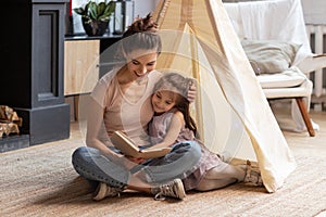 Mother and preschooler daughter hugging read fairytale