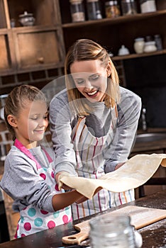 mother and preteen daughter in aprons making cookies together