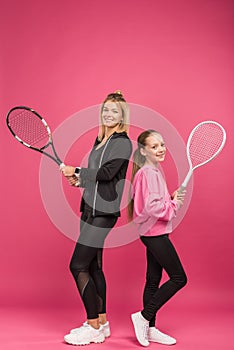 mother and preteen daughter holding tennis rackets, isolated