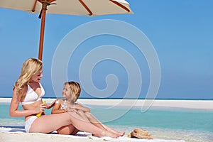 Mother Protecting Daughter With Sun Lotion On Beach Holiday