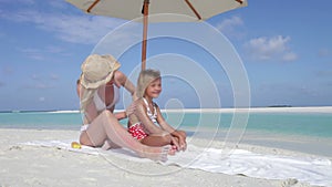 Mother Protecting Daughter With Sun Lotion On Beach Holiday