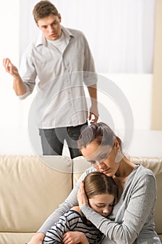 Mother protecting her daughter from angry father photo