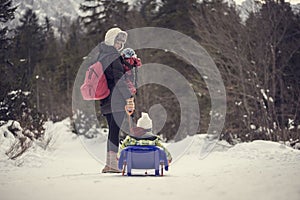 Madre tirando suo attraverso la neve sul slitta 