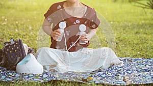 Mother pumping breastmilk in park at sunset