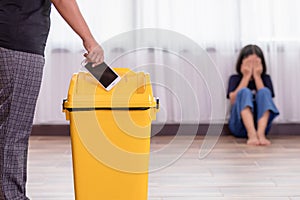 Mother punishing her daughter with throwing smartphone into yellow trash